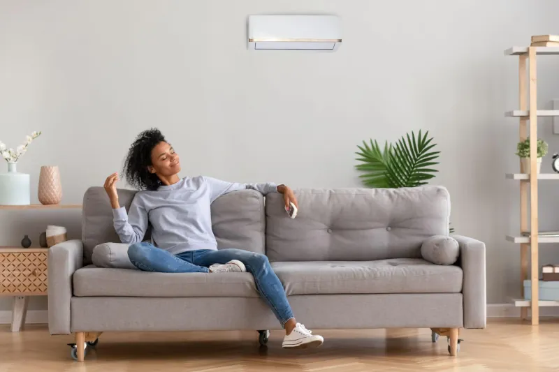 Woman on couch enjoying her ductless AC 's cooling power - Peter Levi