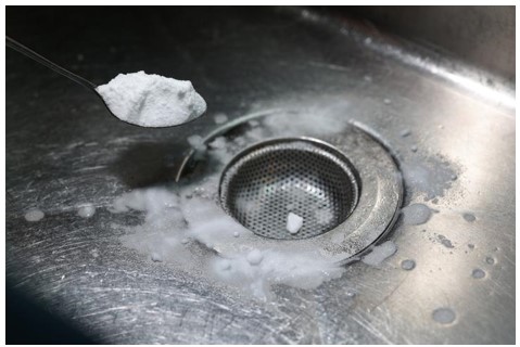 baking soda being put down a sink drain to clean it