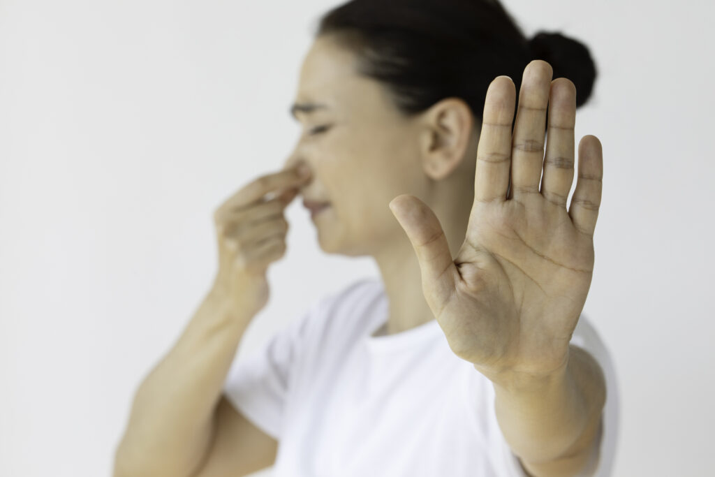 Caucasian female holding nose and showing stop gesture. Representing bad smell.